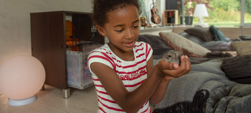 A girl holding her hamster with the Qute cage in the background