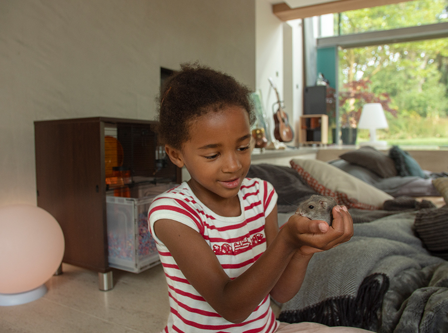 A girl holding her hamster with the Qute cage in the background