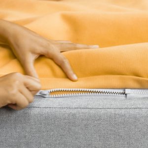 Hands zipping off the machine-washable yellow beanbag topper 