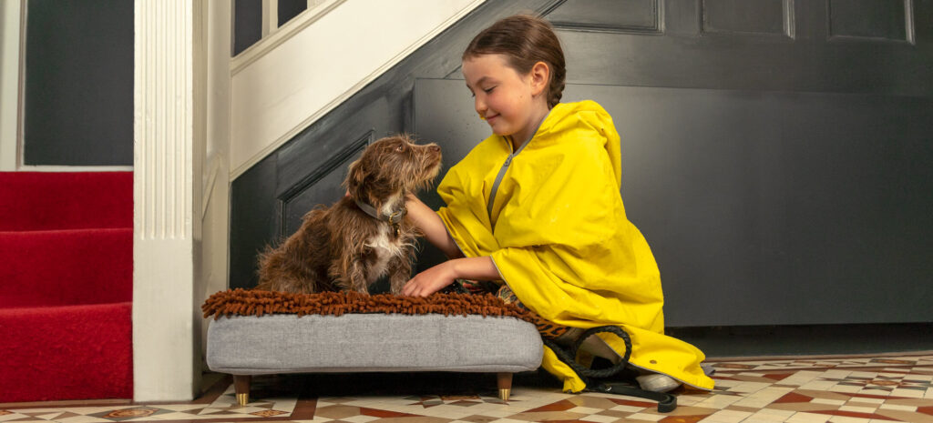 Meisje aait een bruine hond op de Topology hondenmand met microvezel topper