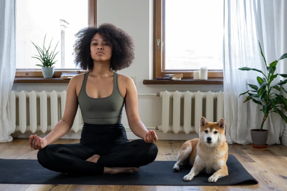 Woman sat on a mat doing doga with her dog