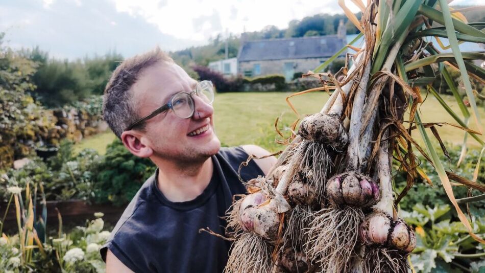 Jude smiling at his home grown garlic